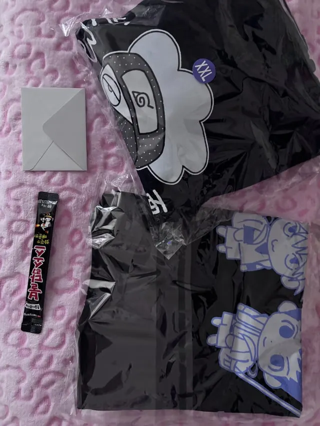 Black character-print clothing in packaging with an envelope and a Korean snack