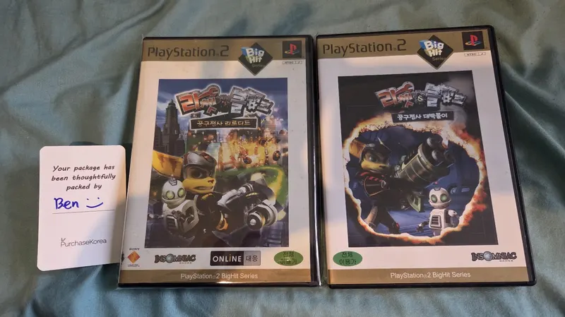 Two Korean PlayStation 2 games beside a handwritten PurchaseKorea packing card
