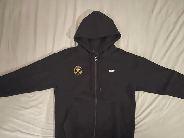 Black zip-up hoodie with an embroidered esports team crest